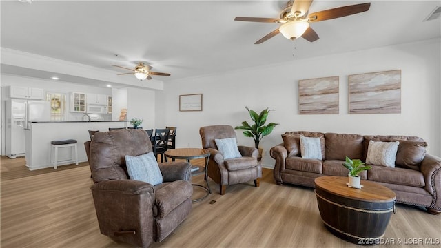 living area with a ceiling fan, visible vents, and light wood-style flooring