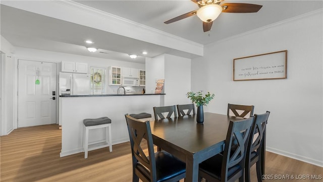 dining area with light wood finished floors, baseboards, crown molding, and recessed lighting