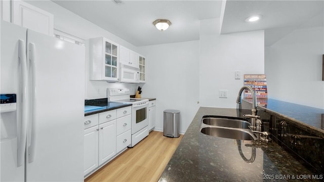 kitchen featuring white appliances, light wood-style flooring, white cabinets, and a sink