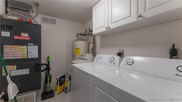 laundry room featuring washer and dryer, electric water heater, cabinet space, and visible vents