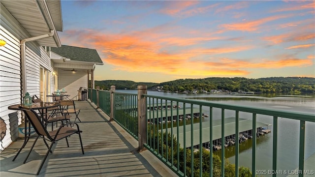 balcony at dusk featuring a water view