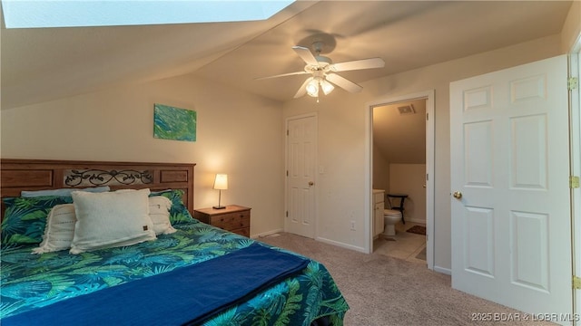 bedroom with light carpet, vaulted ceiling with skylight, visible vents, baseboards, and ensuite bathroom