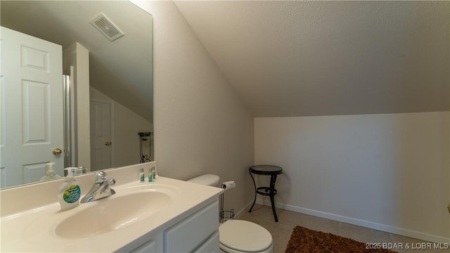 bathroom featuring lofted ceiling, toilet, vanity, visible vents, and baseboards