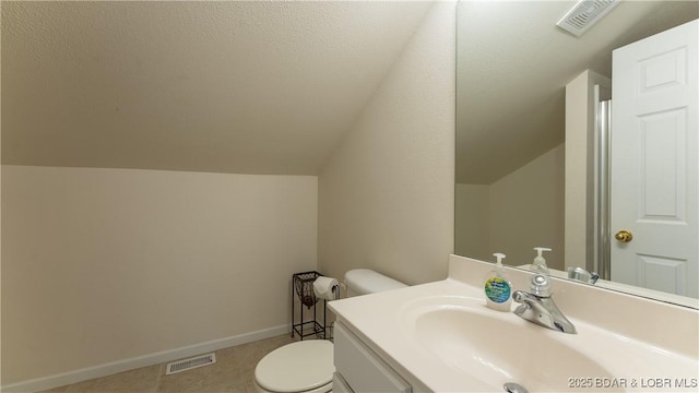 bathroom with lofted ceiling, visible vents, toilet, vanity, and baseboards