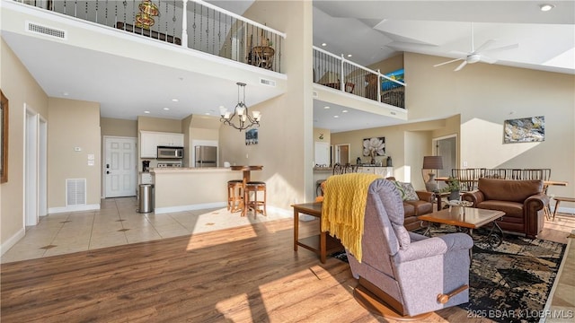 living room featuring ceiling fan with notable chandelier, visible vents, and light wood-style floors