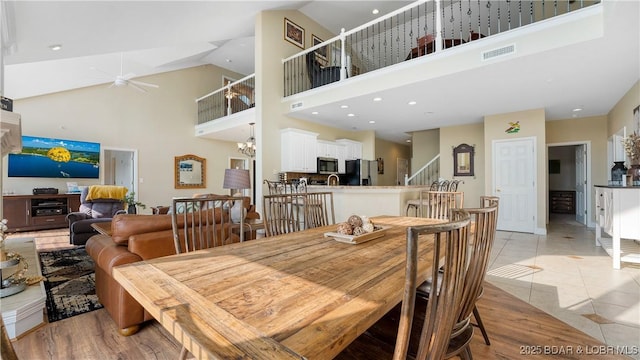 dining space with a chandelier, visible vents, stairway, and a high ceiling