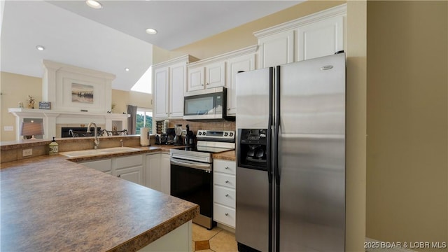 kitchen featuring dark countertops, appliances with stainless steel finishes, white cabinets, and a sink