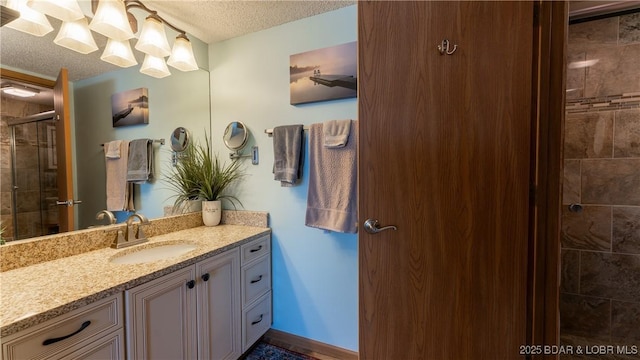 full bath with a stall shower, baseboards, a textured ceiling, and vanity