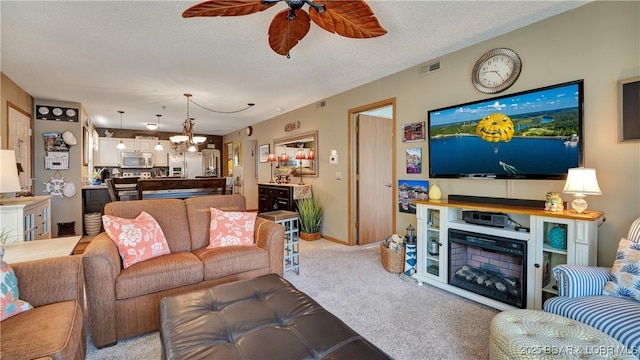 living room featuring light colored carpet, visible vents, a textured ceiling, and ceiling fan with notable chandelier