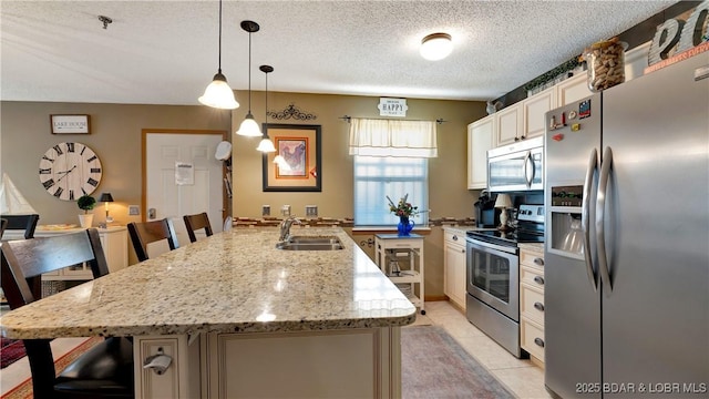 kitchen with a textured ceiling, stainless steel appliances, a sink, a kitchen breakfast bar, and hanging light fixtures