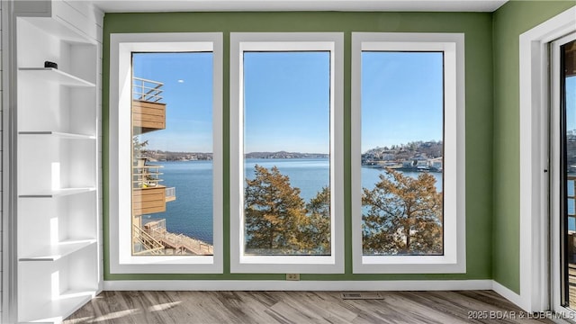 entryway featuring a water view, visible vents, baseboards, and wood finished floors