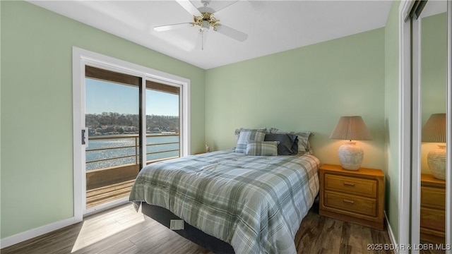 bedroom with a water view, access to exterior, baseboards, and wood finished floors