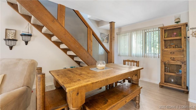 dining area featuring light wood-style flooring, stairway, and baseboards