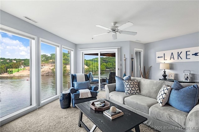 living area featuring visible vents, a water view, light carpet, and ceiling fan