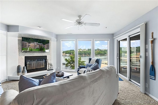 living area with carpet, a glass covered fireplace, ceiling fan, and baseboards