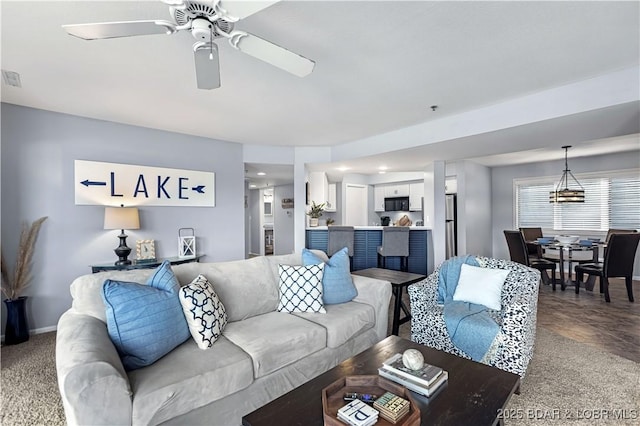 carpeted living area featuring a ceiling fan and baseboards