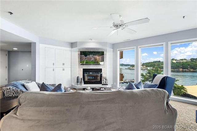 living room featuring a ceiling fan, a wealth of natural light, and a glass covered fireplace