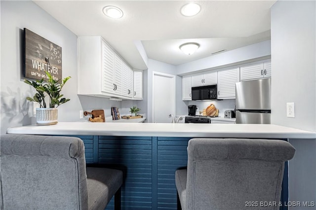 kitchen with white cabinets, a peninsula, and black appliances