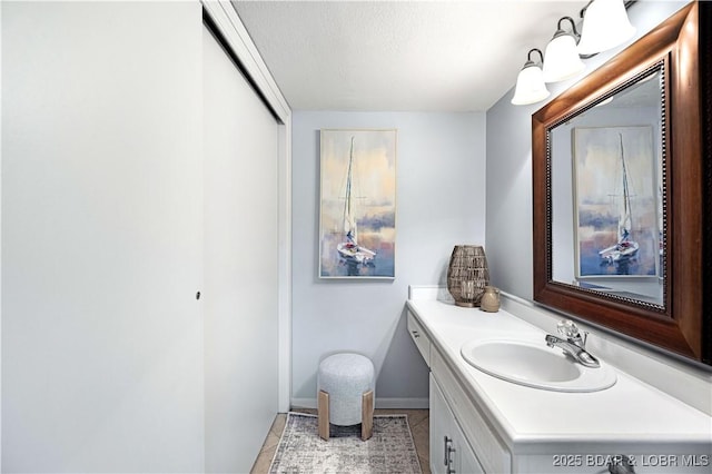 bathroom featuring baseboards, vanity, a textured ceiling, and tile patterned floors