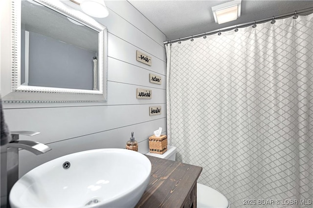 bathroom with a textured ceiling, curtained shower, a sink, and toilet