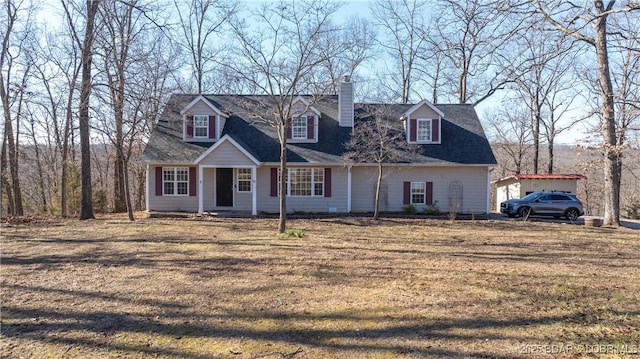 new england style home with a shingled roof, a chimney, and a front lawn