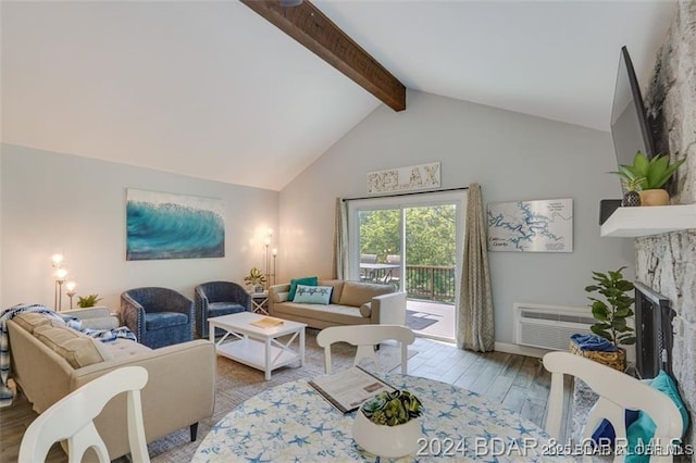 living room with a wall unit AC, beamed ceiling, wood finished floors, a fireplace, and high vaulted ceiling