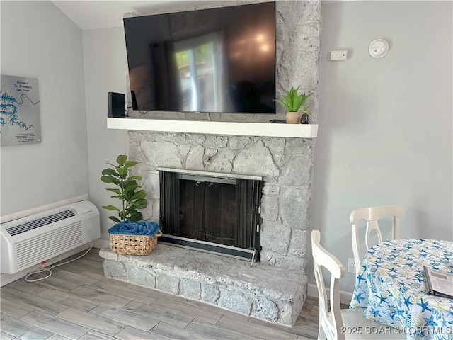 details with wood tiled floor, a wall unit AC, a fireplace, and baseboards