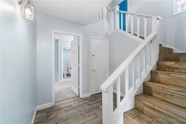 staircase with baseboards and wood finished floors