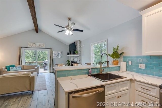 kitchen featuring open floor plan, a sink, a peninsula, and stainless steel dishwasher