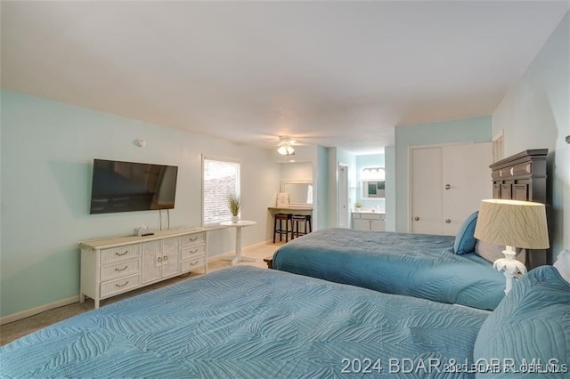 carpeted bedroom featuring connected bathroom and baseboards