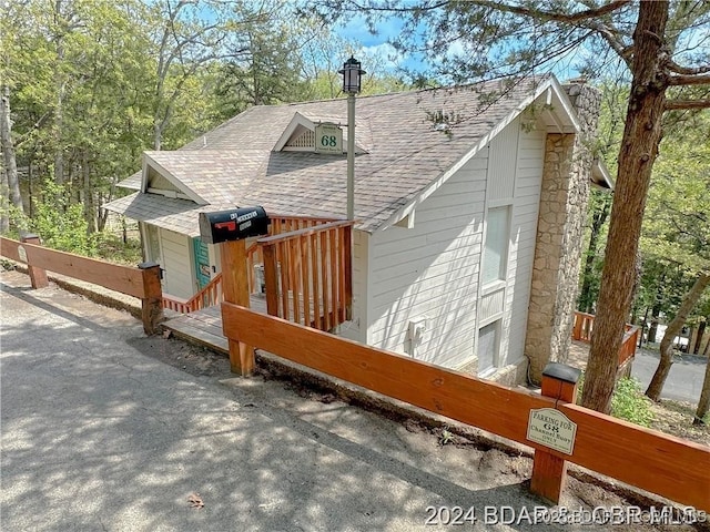 view of side of property with roof with shingles and a chimney