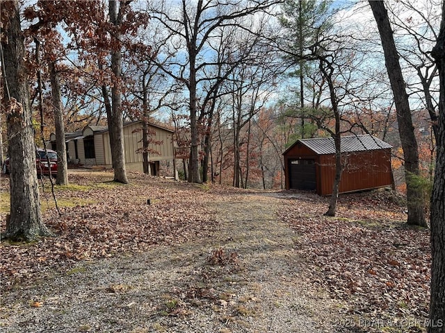 view of yard with an outdoor structure, a detached garage, and dirt driveway