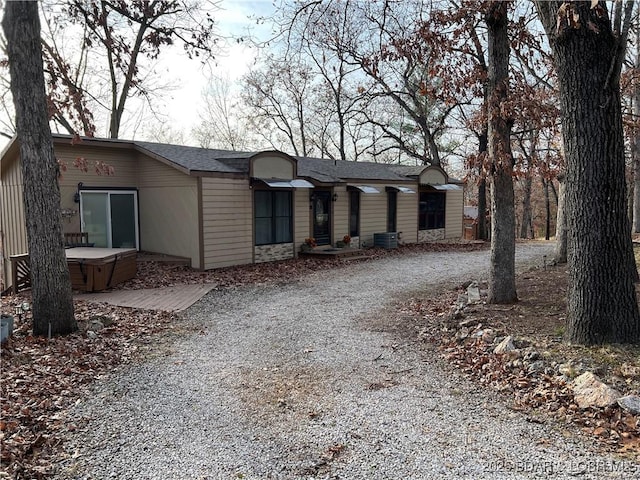 view of front of home with driveway, a hot tub, and roof with shingles