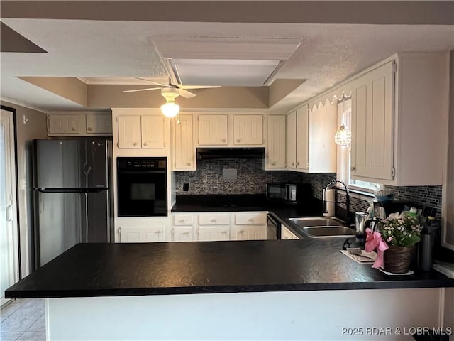 kitchen featuring tasteful backsplash, dark countertops, a sink, a peninsula, and black appliances