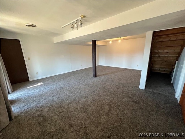 finished basement with baseboards, visible vents, dark colored carpet, and track lighting