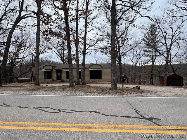 view of front of property featuring an outbuilding and roof with shingles