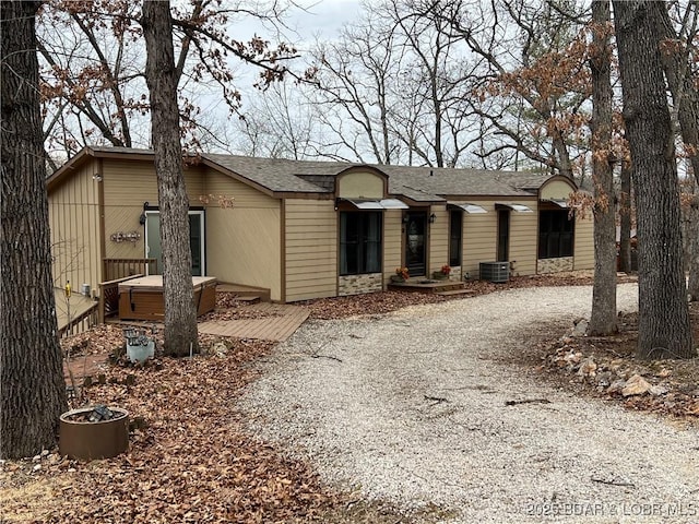 ranch-style house with driveway, cooling unit, and roof with shingles