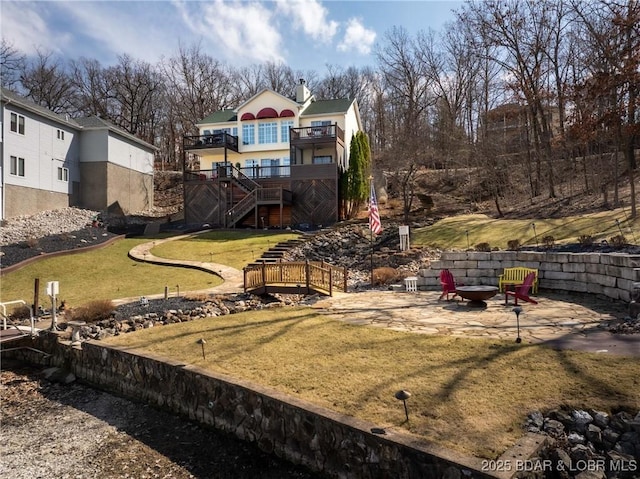 back of property featuring a patio, a lawn, a fire pit, a wooden deck, and stairs