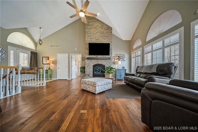 living room with high vaulted ceiling, a large fireplace, visible vents, a ceiling fan, and wood-type flooring