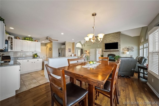 dining area with a fireplace, recessed lighting, vaulted ceiling, wood finished floors, and ceiling fan with notable chandelier