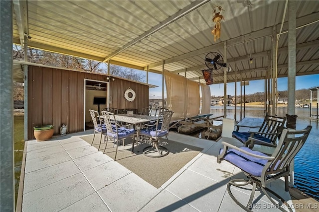 view of patio with an outbuilding, outdoor dining area, a dock, and a water view