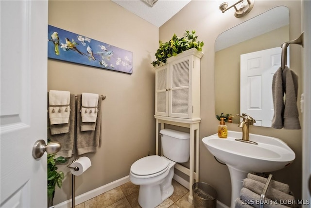 half bathroom featuring visible vents, baseboards, toilet, tile patterned floors, and a sink