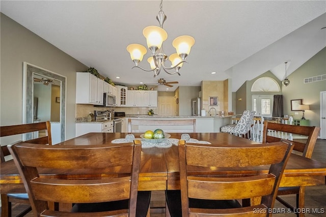 dining area with lofted ceiling, visible vents, and ceiling fan with notable chandelier