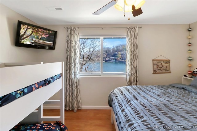 bedroom featuring a ceiling fan, baseboards, visible vents, and wood finished floors