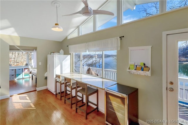 dining room with wine cooler, a ceiling fan, wood finished floors, high vaulted ceiling, and baseboards