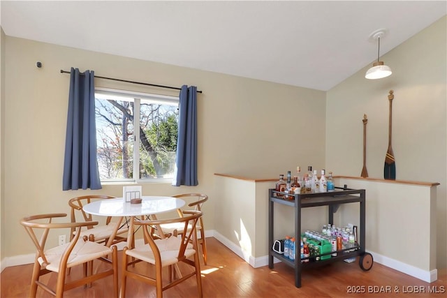 dining space with lofted ceiling, baseboards, and wood finished floors