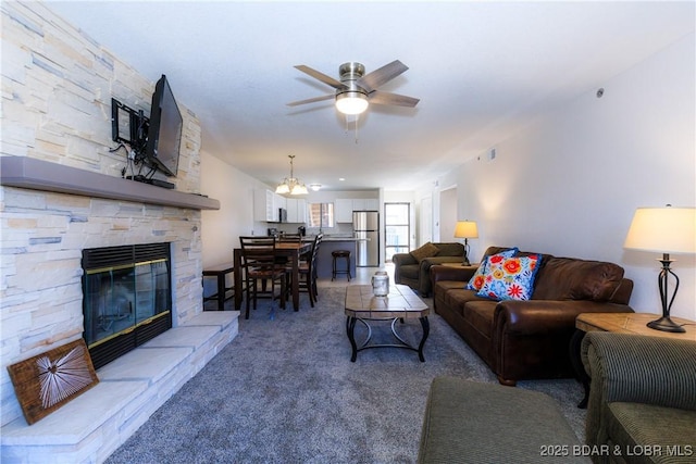 living room featuring visible vents, light colored carpet, ceiling fan, and a stone fireplace