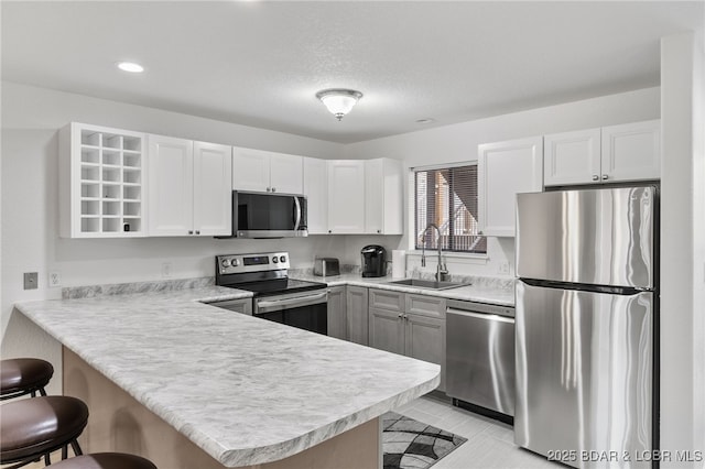 kitchen featuring a sink, a kitchen breakfast bar, appliances with stainless steel finishes, a peninsula, and light countertops