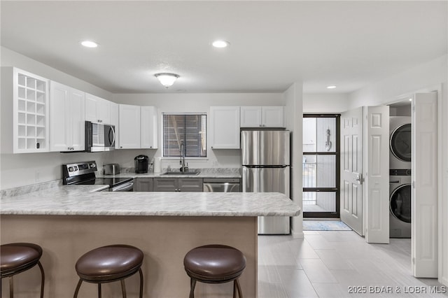 611 Lazy Days Rd Unit V-7, Osage Beach, MO 65065 - kitchen with a sink, a breakfast bar area, stainless steel appliances, a peninsula, and stacked washer and dryer