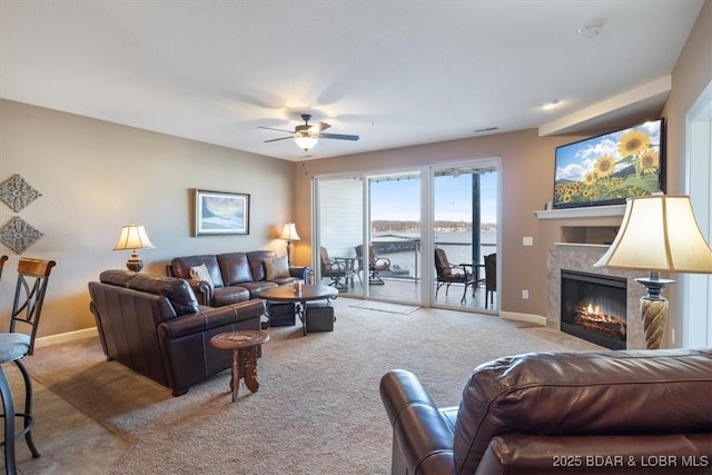 living area with carpet floors, ceiling fan, baseboards, and a tile fireplace